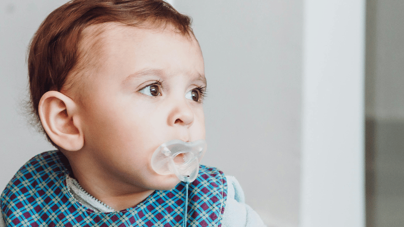 A baby is using a rubber pacifier